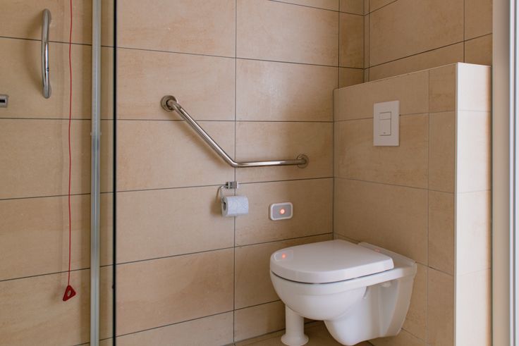 Verhoogd toilet met handgrepen en een alarmkoord