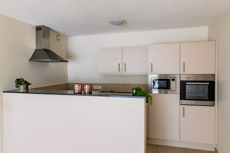 Ingerichte keuken met werkblad, dampkap, oven en microgolfoven