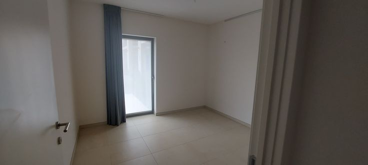 Lege slaapkamer met een raam naar buiten en een donker gordijn