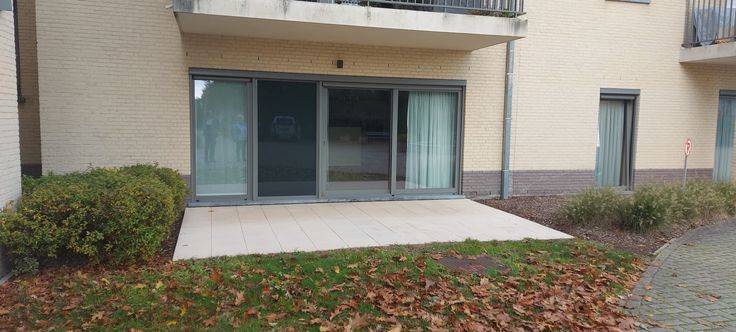 Gevel van de woning op het gelijkvloers, met schuiframen en een terras